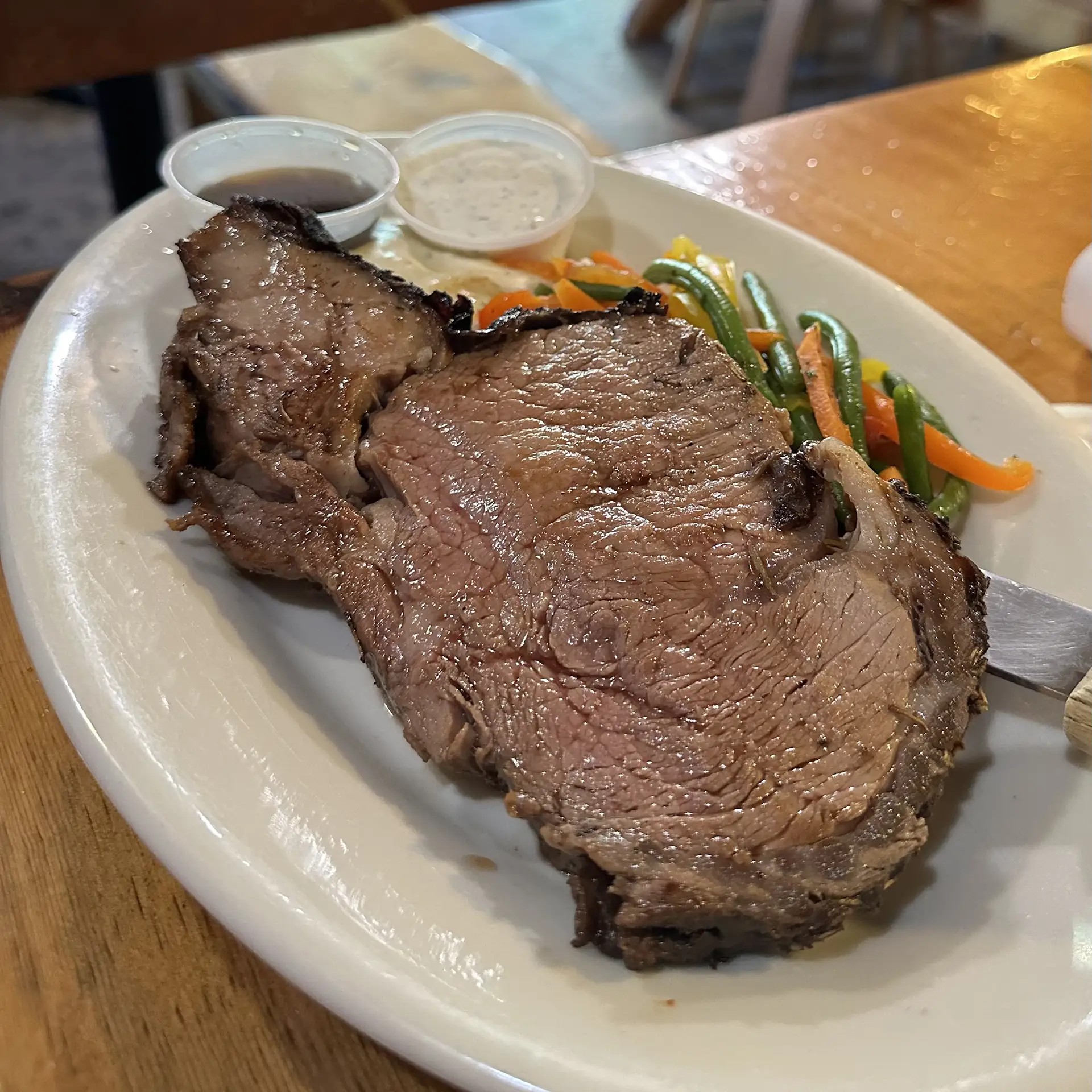 A juicy ribeye steak served with mixed vegetables and dipping sauces.
