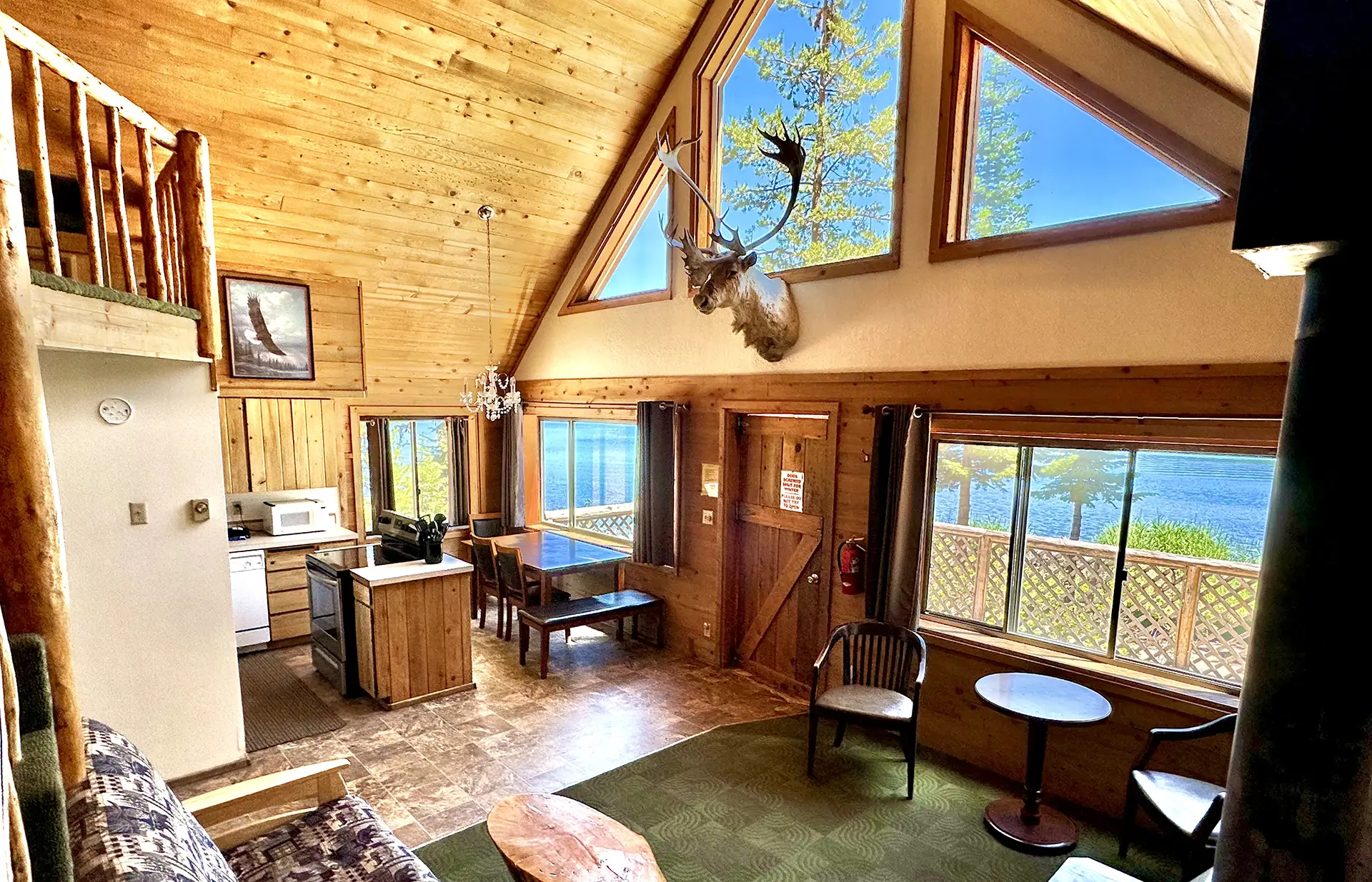 Cozy interior of a wooden cabin featuring large windows with lake views.