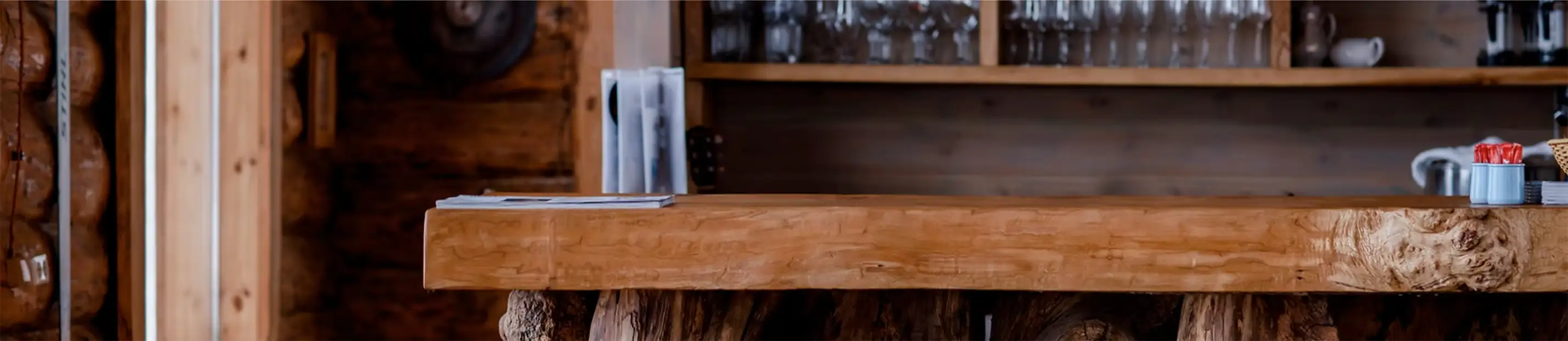 Wooden bar countertop with a backdrop of glasses and rustic decor.