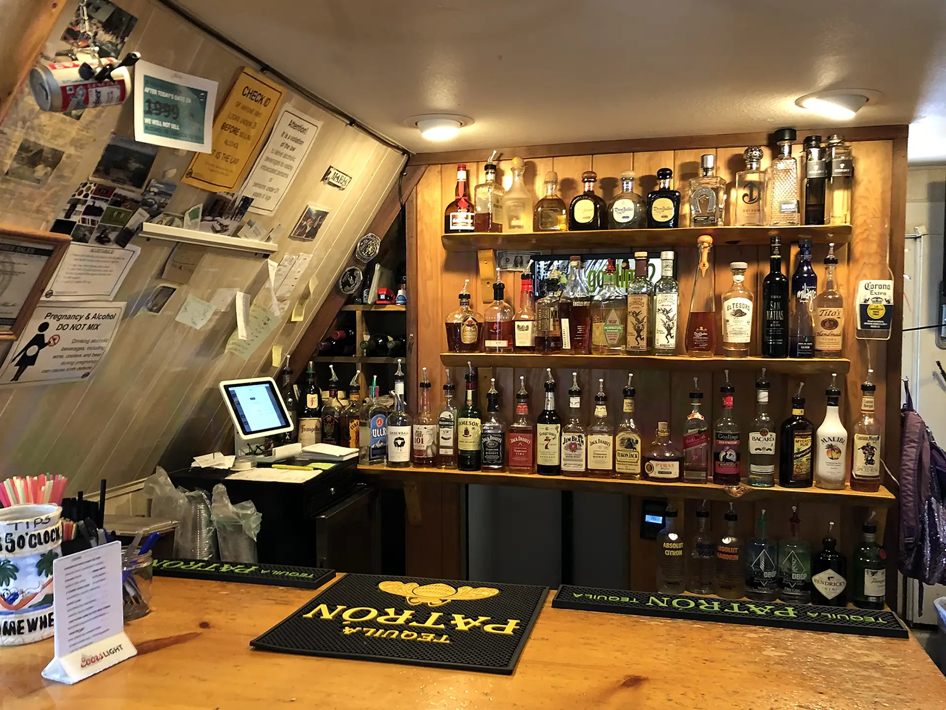 A well-stocked bar featuring various bottles of liquor on shelves behind a wooden counter.