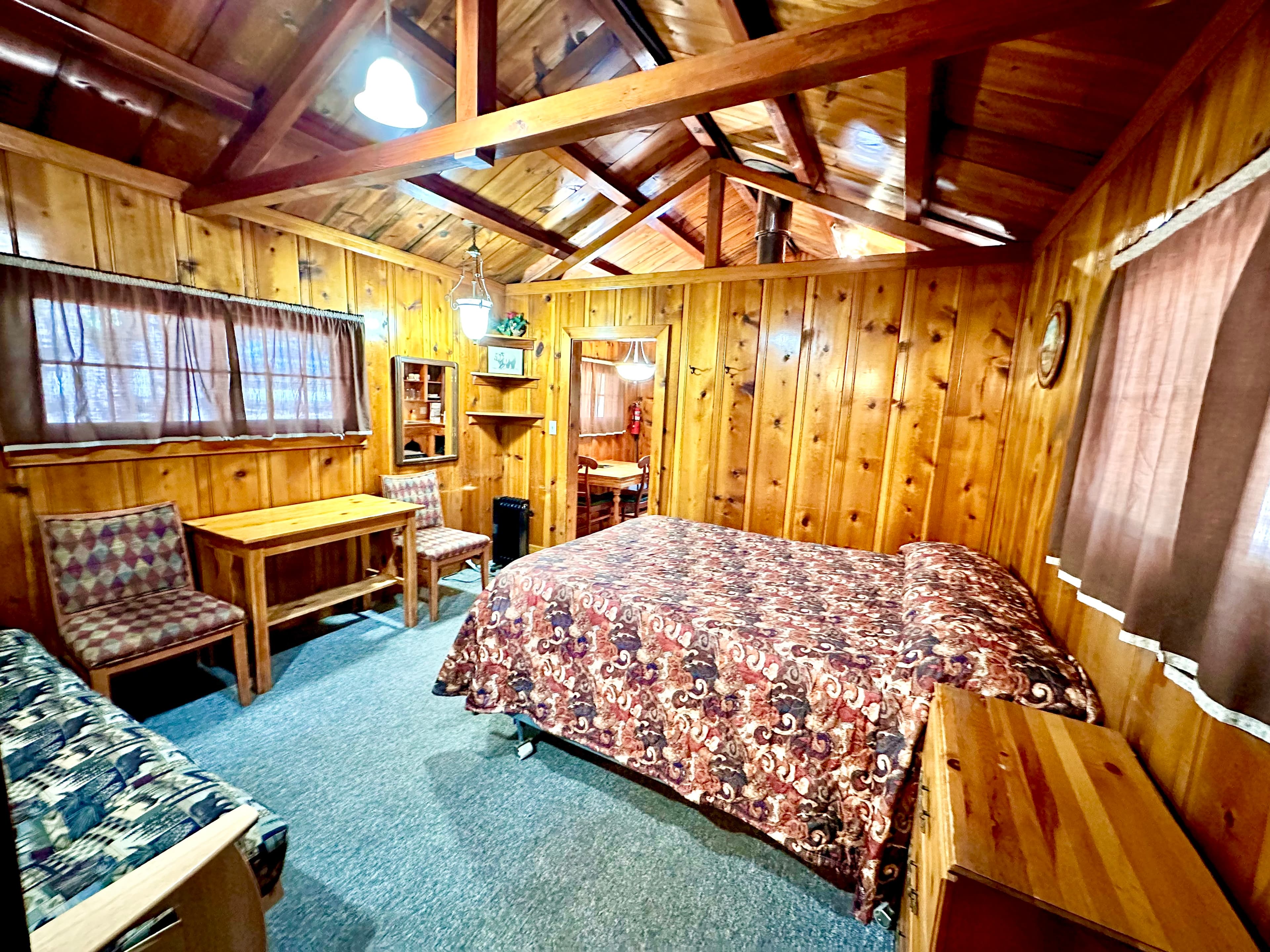 Cozy wooden cabin interior featuring a bed, seating area, and dining table.