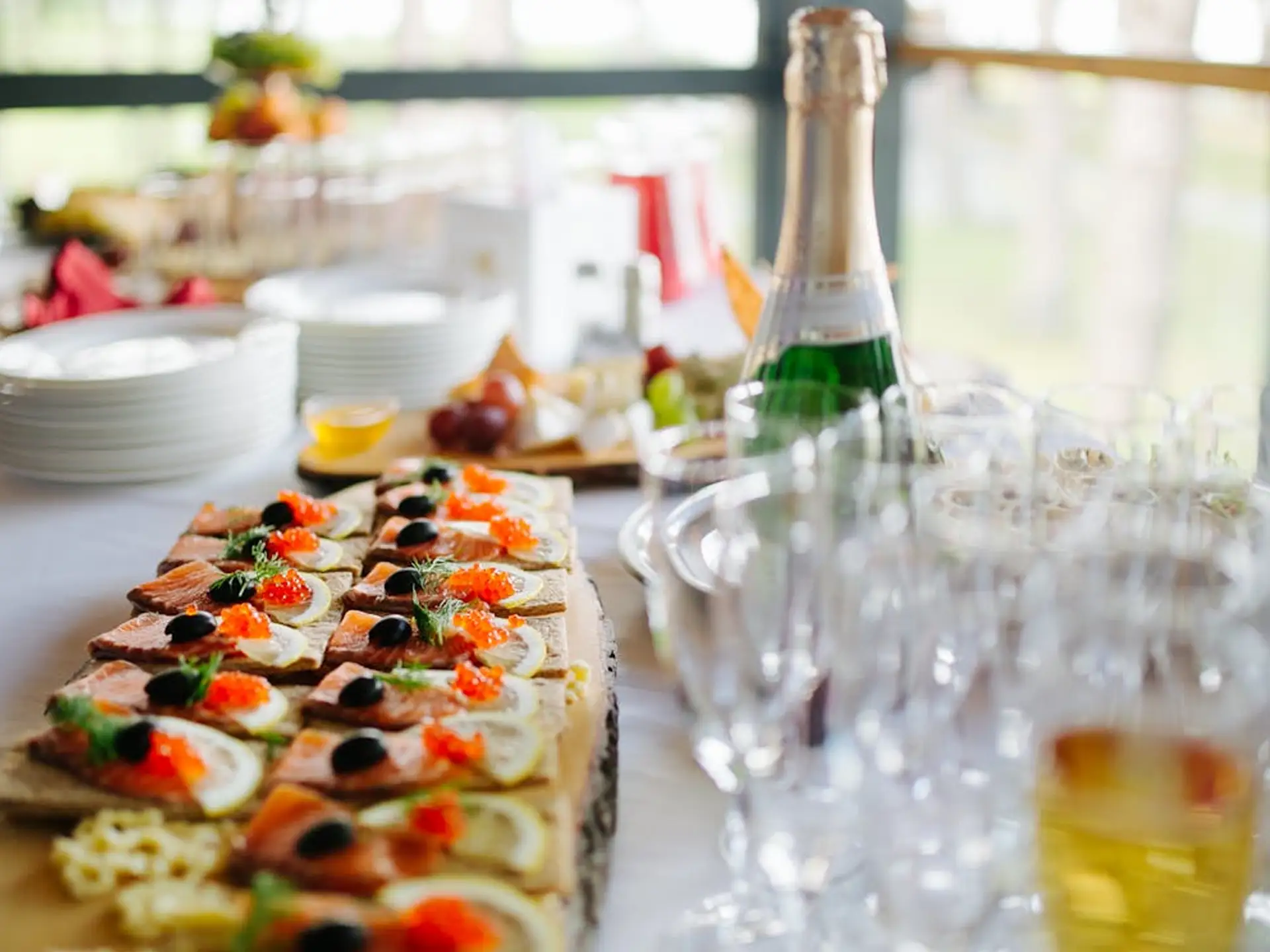 A table spread with gourmet appetizers, champagne, and an array of empty glasses.