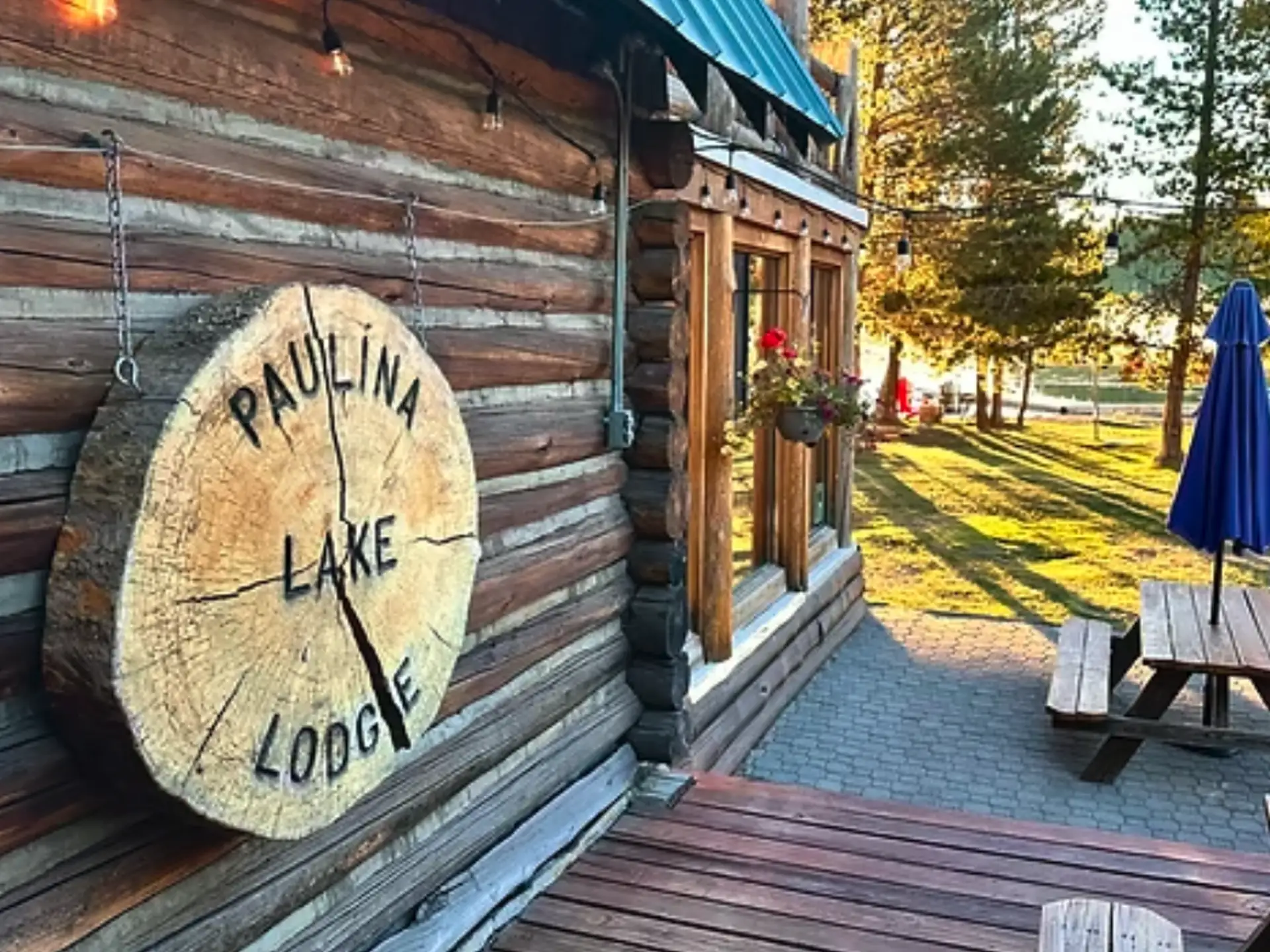 A wooden sign reading "Paulina Lake Lodge" hangs next to a log cabin.