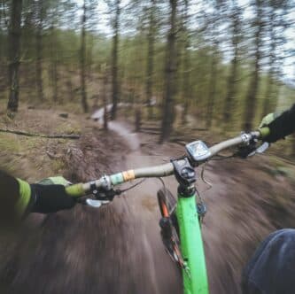A cyclist navigates a twisting mountain bike trail through a wooded area.