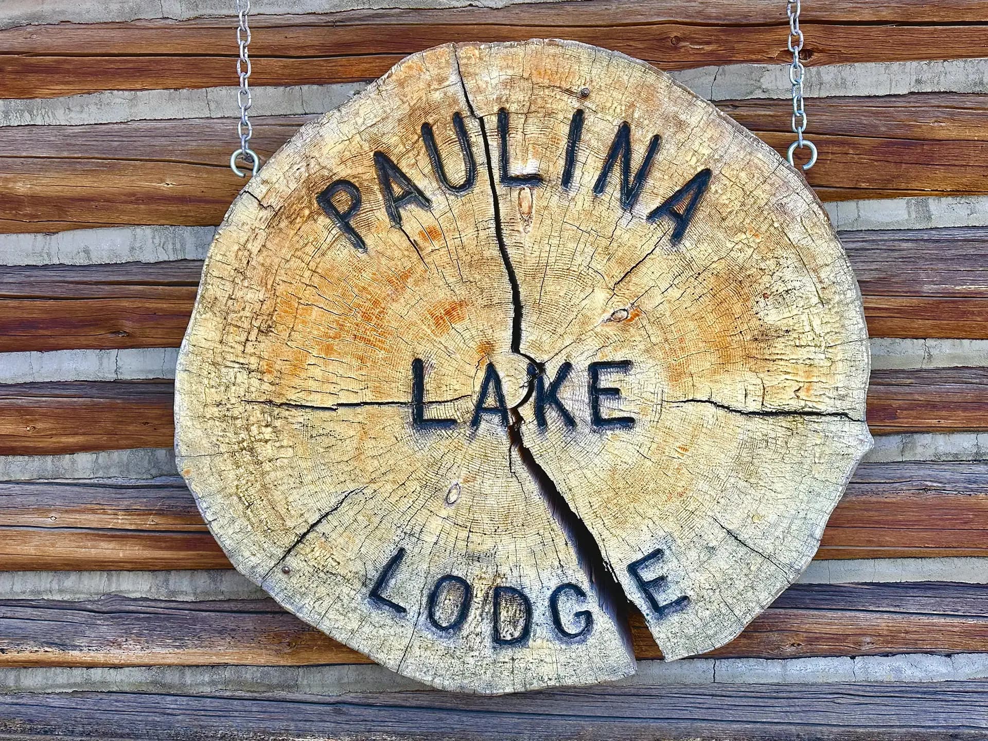Wooden sign reading "Paulina Lake Lodge" on a rustic background.