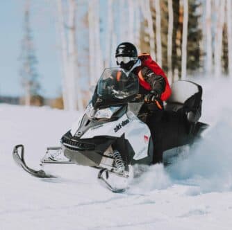 A person riding a snowmobile through a snowy landscape.